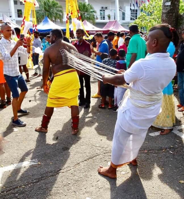 Thaipusam, fishhooks in back with friend pulling on them