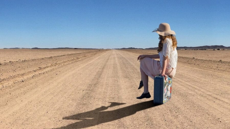 Girl sitting on suitcase-moving to a foreign country