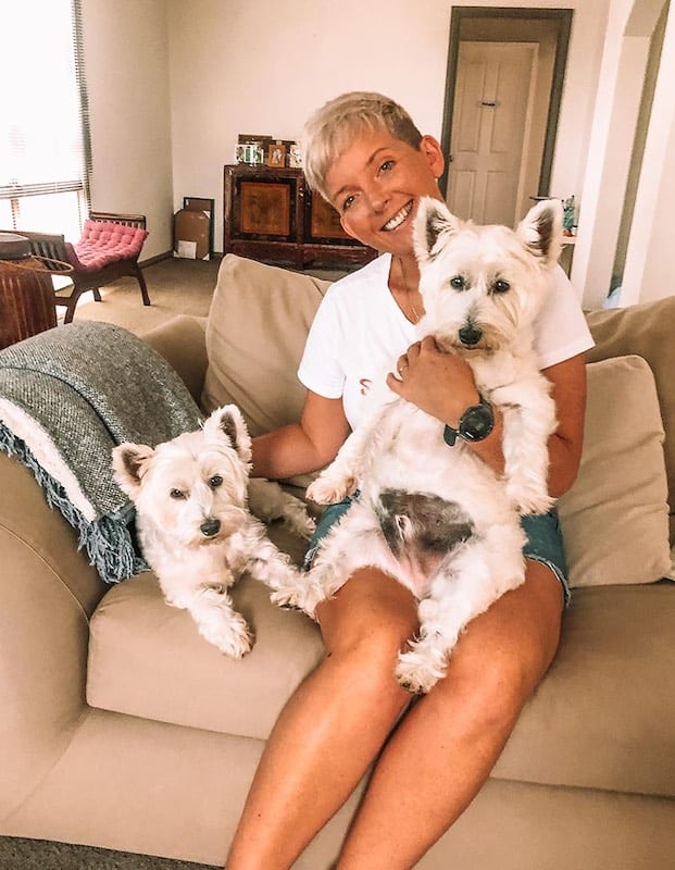 Blonde girl with 2 white dogs in her lap