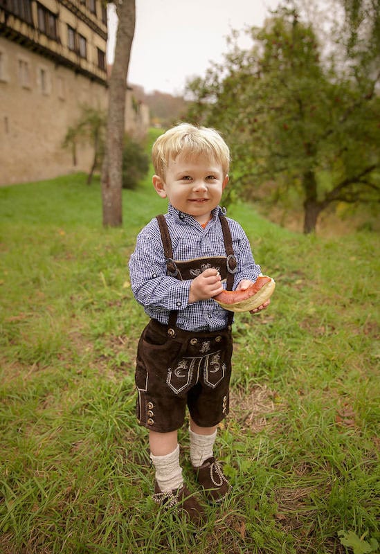 blonde boy in grass wearing lederhosen: multicultural kids