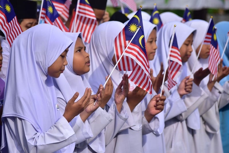 Girls waving flags for Merdeka Day