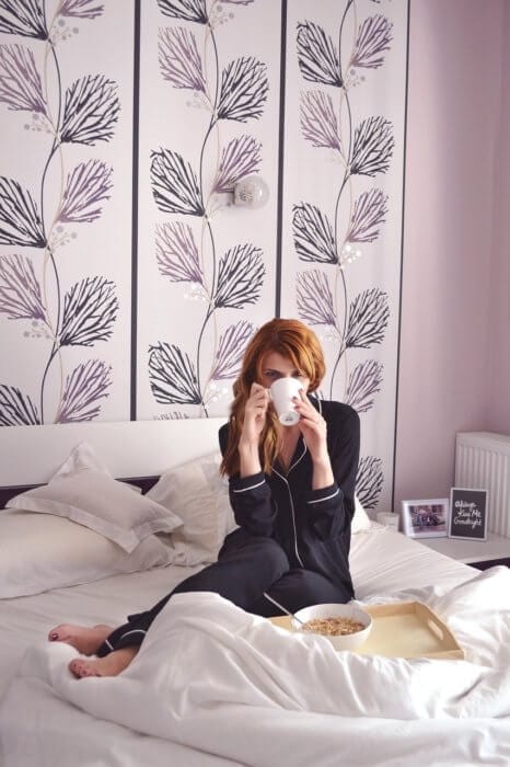 Girl in bed with black pjs drinking coffee