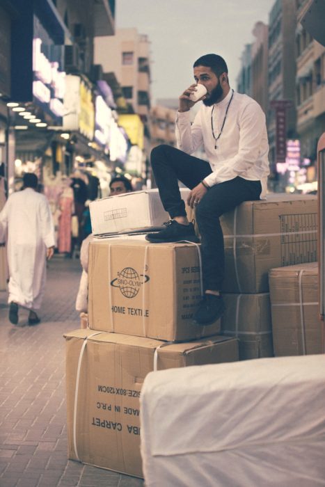 guy sitting on top of boxes: checklist for moving abroad