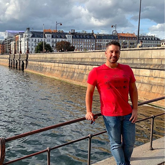 Guy in red shirt in front of water-expat in Denmark