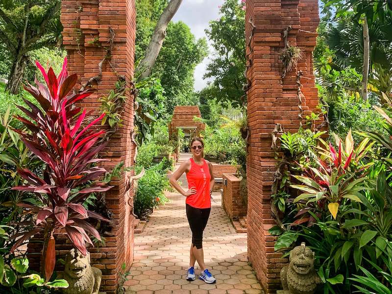 Emma in red top standing in an exotic garden