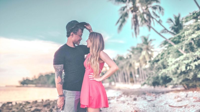 beautiful couple on the beach staring into each others eyes.