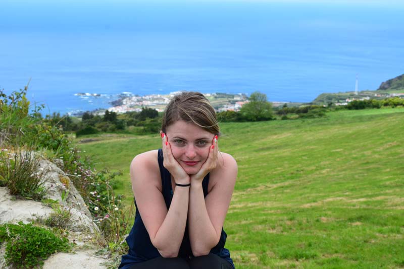 Alexandrina with hands on face with ocean behind her.