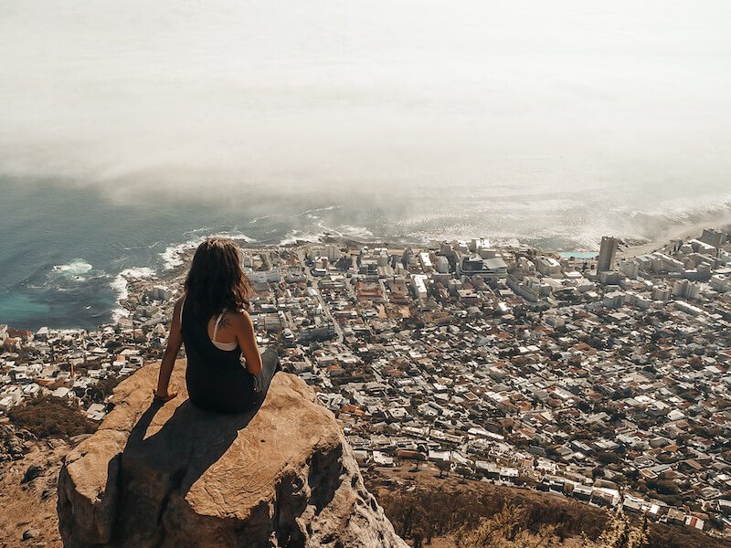 Kathi sitting on top of rock overlooking a city by the ocean