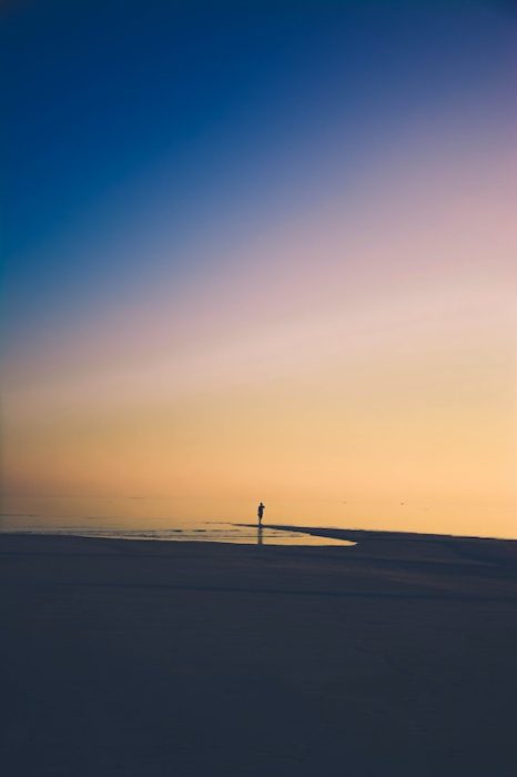 moving away from family can be lonely. person alone on the beach at sunset