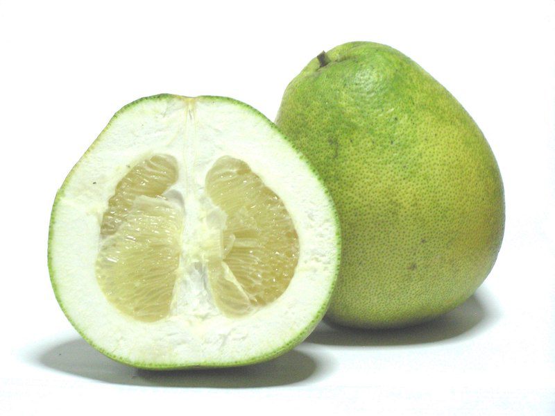 2 pomelos, one is cut in half and the other is whole.  