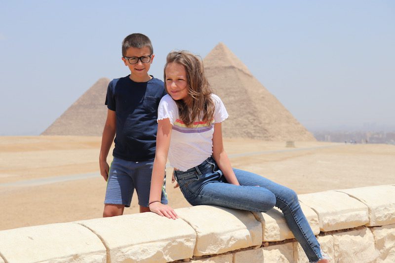 a girl and a boy in front of the pyramids in Egypt
