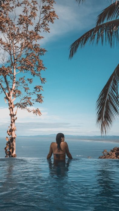 Woman in an infinity pool overlooking the ocean. You can have this if you live in Malaysia.