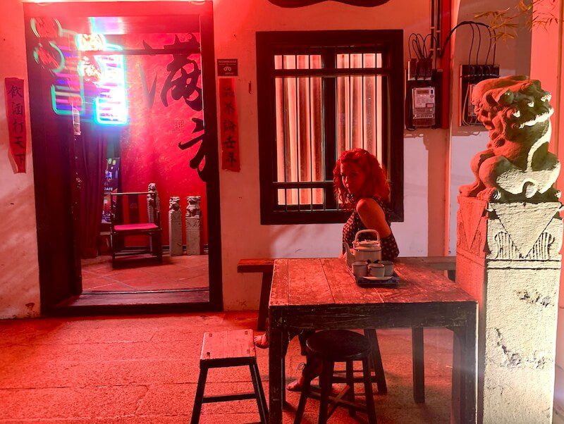 girl sitting outside under red lights