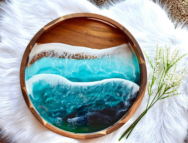 circular wooden tray with blue ocean waves made of epoxy on it. Its a gorgeous gift for beach lovers
