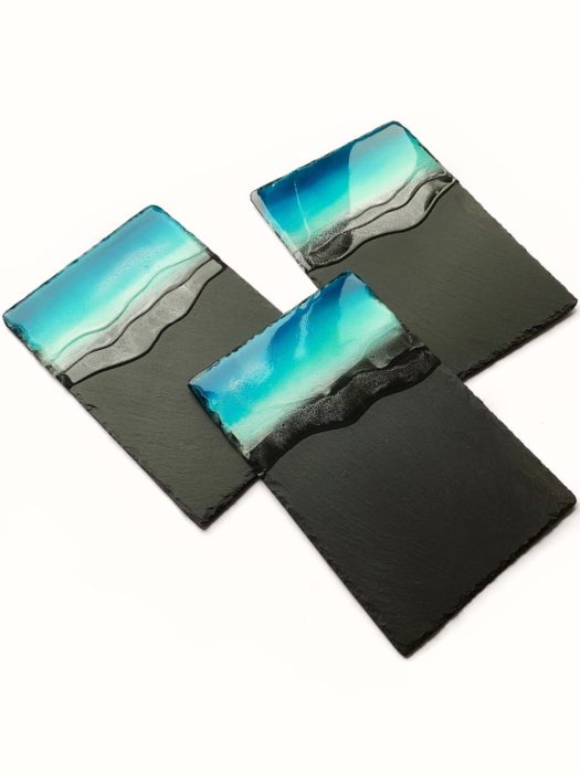 3 black slate serving trays dipped in blue epoxy to make it look like the ocean