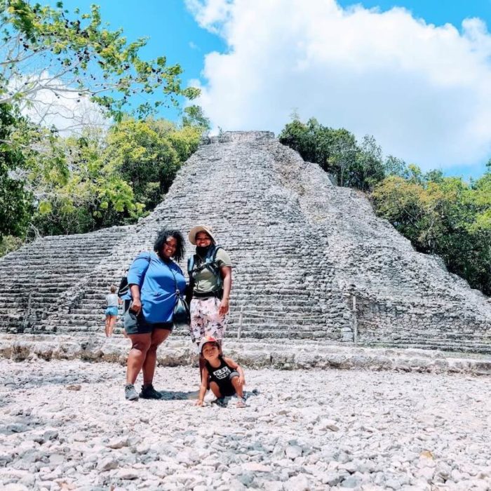 happy nomad family of 2 ladies and child in front of a Aztec ruin in Mexico