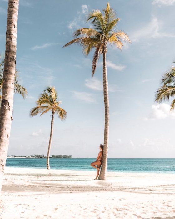 girl living in a foreign country leaning on a palm tree