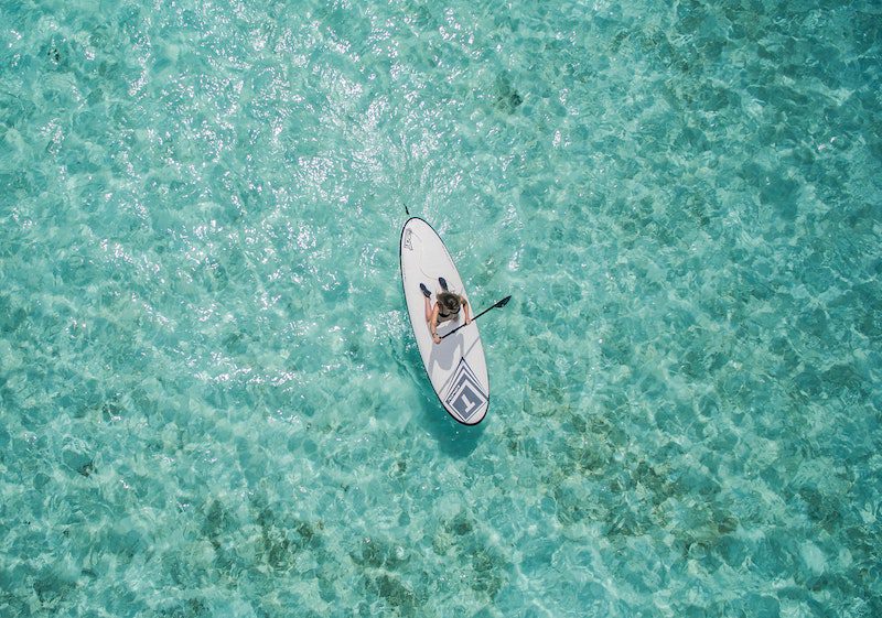 girl paddleboarding over clear blue ocean: living in a foreign country