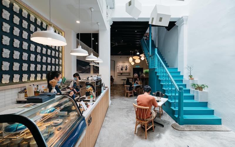 a cute Penang cafe with white walls and a turquoise staircase