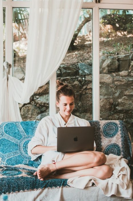 blogger sitting on her couch with a laptop. A blogger is a good job for digital nomads