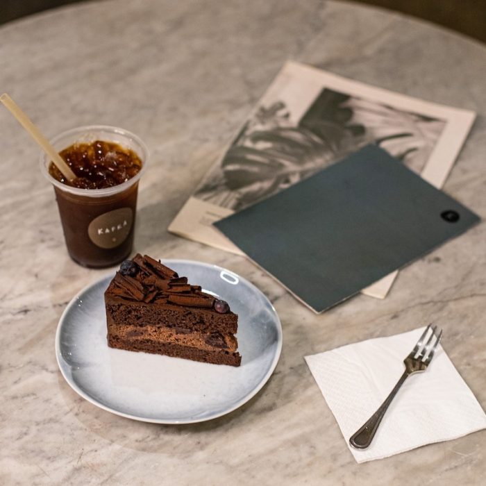 chocolate cake, iced coffee and a grey folder. 