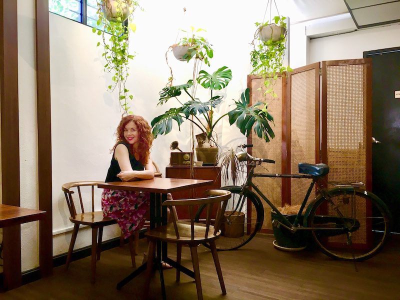 girl in a Penang cafe by a bike and plants