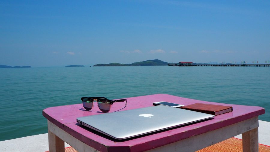 Closed Mac on a pink table in front of the ocean 