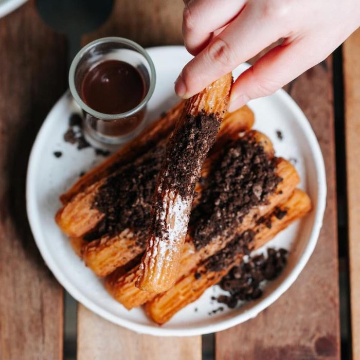 A plate full of churros with chocolate crumbles on top