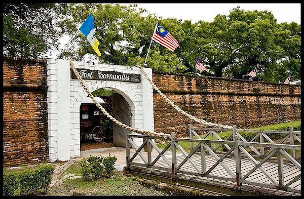 Entrance to Fort Cornwallis is a moat with two flags and and archway 