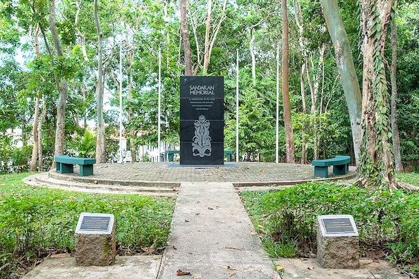 Sandakan Memeorial park with a tall plaque and benches to sit at.