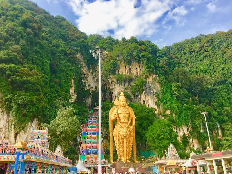 Batu Caves in Kuala Lumpur are one of the most historical places in Malaysia with a rainbow staircase and a tall gold statue of Lord Murugan.