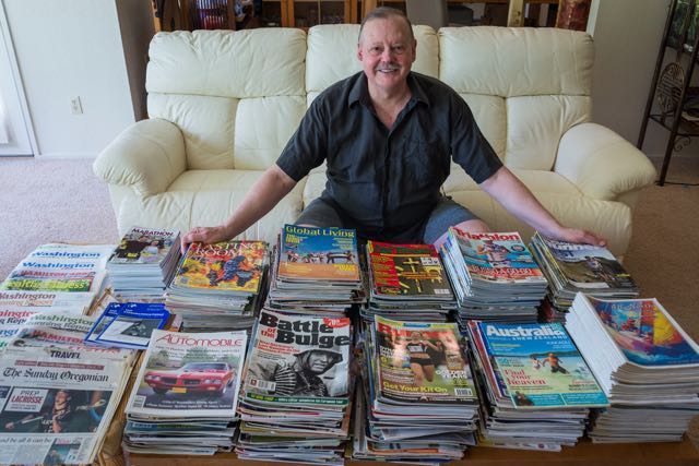 man in front of stack of magazines 