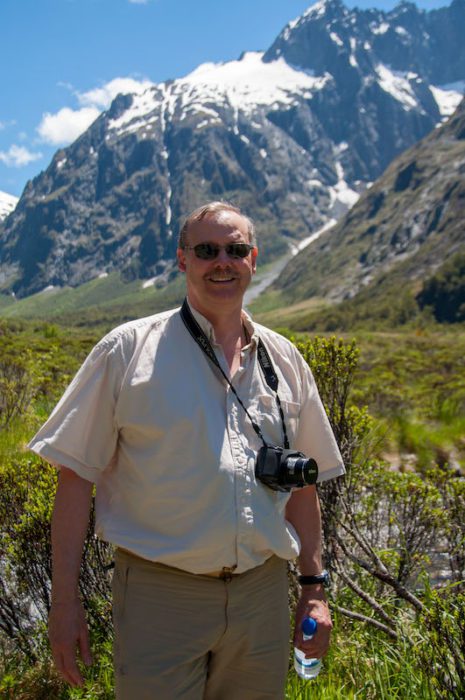 man standing in front of mountain with camera