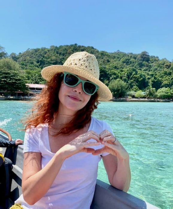 girl in boat with hat and blue sunnies