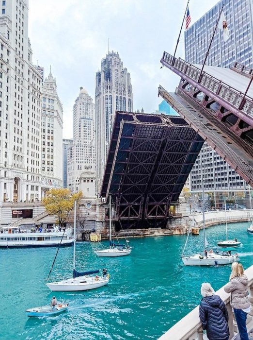 raised bridge in chicago with boats in the river