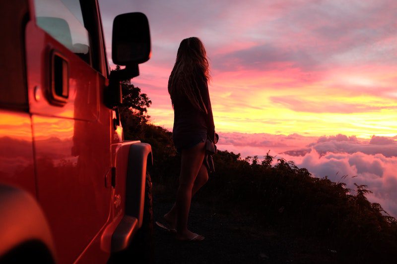 girl standing my jeep at sunset