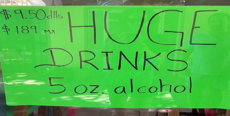 green sign saying HUGE DRINKS 5 oz alcohol.