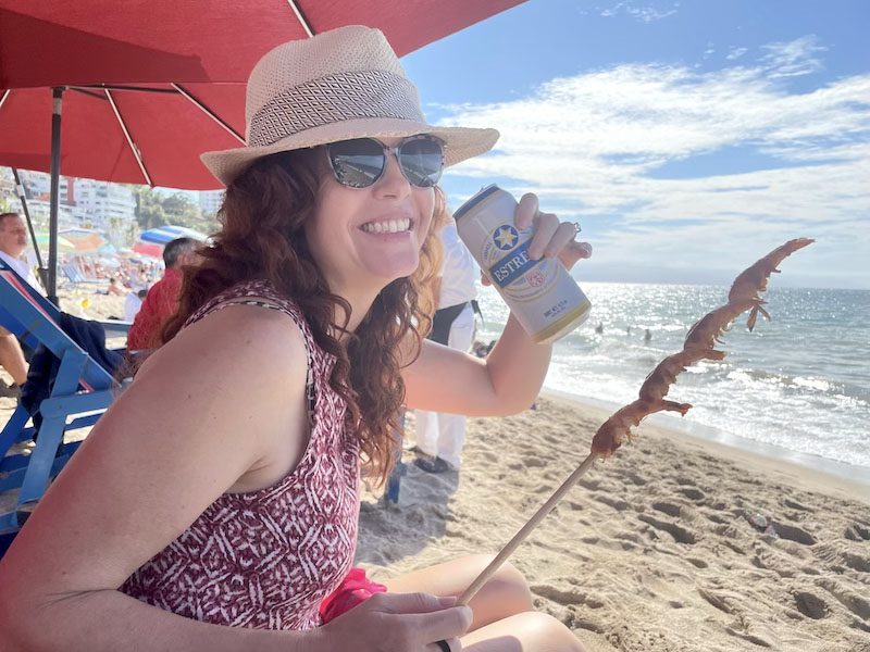 Me at Swell beach bar drinking a beer with a stick of shrimp