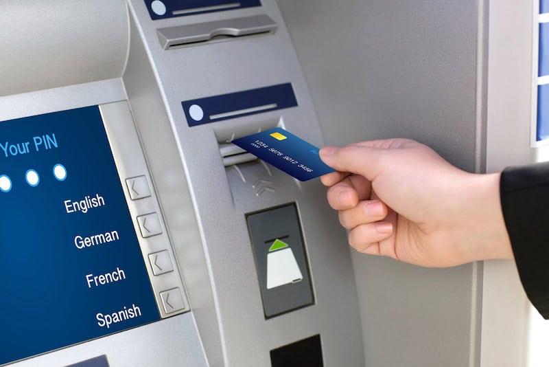 person putting bank card into ATM machine